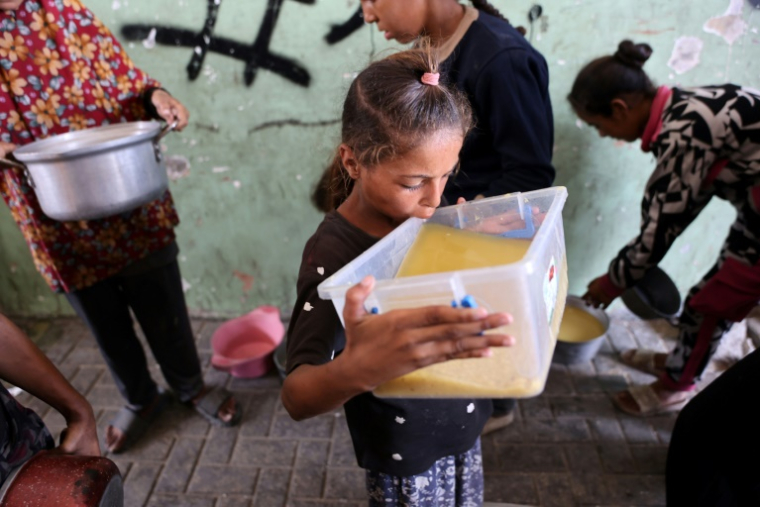 Une fillette palestinienne prend une gorgée d'une soupe aux lentilles reçue à un point de distribution de nourriture dans la ville de Gaza, le 25 juillet 2025 ( AFP / Omar AL-QATTAA )