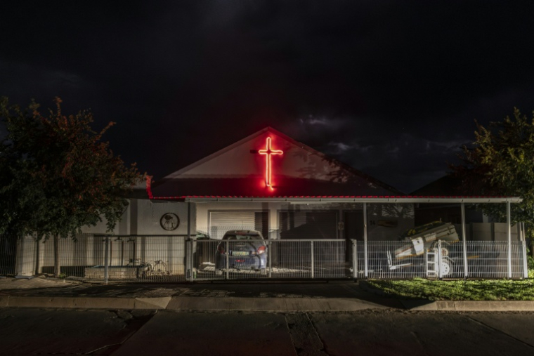 Une croix de lumière rouge orne la façade de la maison d'habitants de l'enclave afrikaner d'Orania en Afrique du Sud, le 28 janvier 2026. ( AFP / CAMILLA RICHETTI )