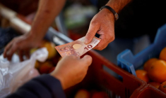 Une cliente paie avec un billet de dix euros sur un marché local de Nantes