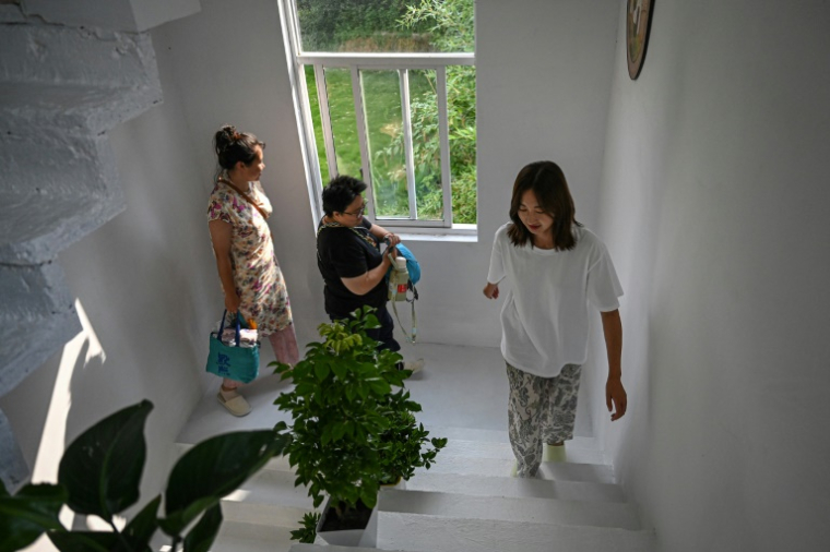 Chen Yani (d), fondatrice du gîte rural "L'Univers imaginaire de Keke", montre aux nouvelles invitées leurs chambres, le 14 juillet 2025 à Hangzhou, dans la province du Zhejiang, dans l'est de la Chine ( AFP / Jade GAO )