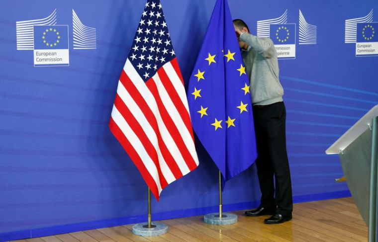 Un employé ajuste les drapeaux de l'UE et des États-Unis au siège de la Commission européenne à Bruxelles