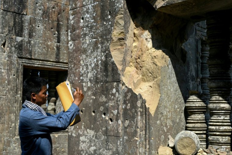 Un homme prend une photo d'une structure endommagée du temple de Preah Vihear, dans le nord du Cambodge, le 6 février 2026 ( AFP / TANG CHHIN Sothy )