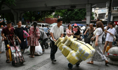 Un homme transportant des ballots de vêtements vers un marché de gros de Canton, en Chine, le 16 avril 2026 ( AFP / Jade GAO )