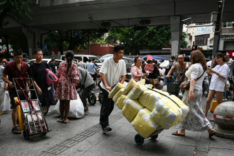 Un homme transportant des ballots de vêtements vers un marché de gros de Canton, en Chine, le 16 avril 2026 ( AFP / Jade GAO )