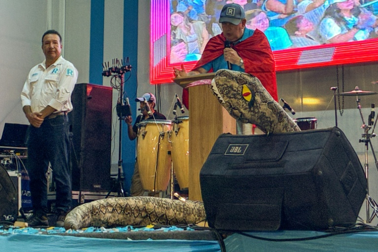 Le candidat à la présidence péruvienne Rafael Lopez Aliaga, du parti Renovacion Popular, avec une marionnette représentant un serpent lors d'un meeting dans le quartier de San Juan de Lurigancho, en banlieue de Lima, le 15 mars 2026 ( AFP / Carlos MANDUJANO )