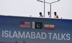 Des passants derrière un panneau sur les négociations entre les Etats-Unis et l'Iran à Islamabad, au Pakistan, le 10 avril 2026 ( AFP / Farooq NAEEM )