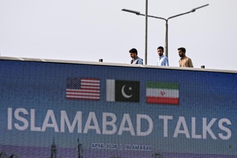 Des passants derrière un panneau sur les négociations entre les Etats-Unis et l'Iran à Islamabad, au Pakistan, le 10 avril 2026 ( AFP / Farooq NAEEM )