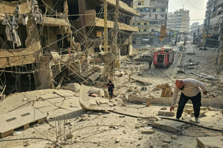 Des pompiers près d'un immeuble détruit  sur le site de frappes aériennes israéliennes nocturnes dans la banlieue sud de Beyrouth, le 12 mars 2026 au Liban ( AFP / - )