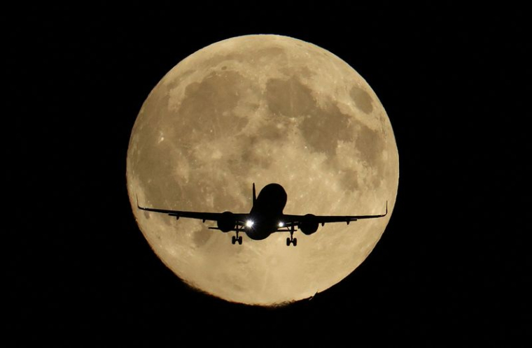 Un avion de ligne survole Londres et passe devant la super lune Harvest Moon
