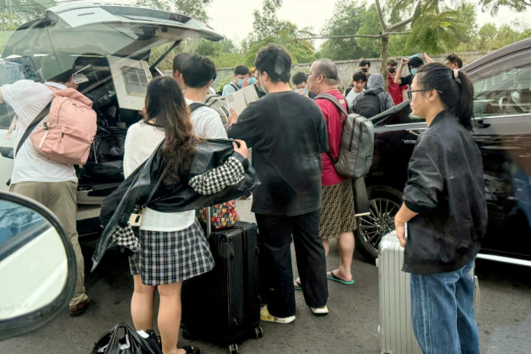 Des personnes chargent leurs bagages dans des véhicules après avoir quitté un complexe soupçonné d'être un centre d'escroquerie à Sihanoukville, le 15 janvier 2026 au Cambodge ( AFP / TANG CHHIN Sothy )