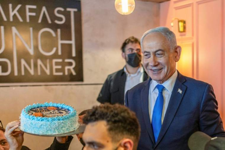 Le Premier ministre israélien Benjamin Netanyahu (d) échange avec des sympathisants venus lui offrir un gâteau pour son 77e anniversaire, lors d’une rencontre dans un café à Dimona, le 21 octobre 2026 en Israël ( AFP / Ilia YEFIMOVICH )