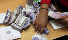 Un vendeur compte des piles de billets de livres sterling