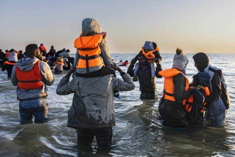 Des migrants avancent dans l'eau pour embarquer sur le bateau d'un passeur et tenter de traverser la Manche au large de la plage de Gravelines, le 16 juin 2025 dans le Nord ( AFP / Sameer Al-DOUMY )
