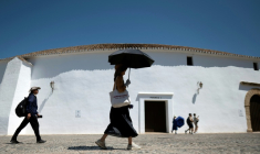 Une femme portant des gants et un chapeau s'abrite du soleil avec un parapluie à Ronda, dans le sud de l'Espagne, le 2 juillet 2025  ( AFP / JORGE GUERRERO )