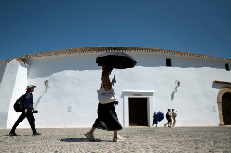 Une femme portant des gants et un chapeau s'abrite du soleil avec un parapluie à Ronda, dans le sud de l'Espagne, le 2 juillet 2025 ( AFP / JORGE GUERRERO )
