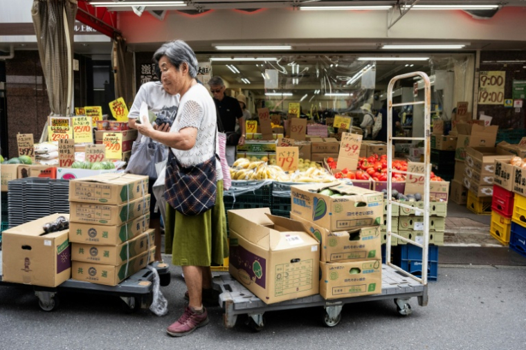 Une cliente achète des légumes sur un marché de Tokyo, le 17 août 2026 ( AFP / Andrew CABALLERO-REYNOLDS )