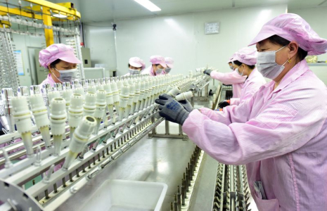 Workers work on a production line manufacturing bottle caps for export at a factory of a packaging company in Lianyungang