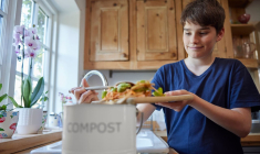 (Crédits photo : Adobe Stock - Adolescent remplissant un seau de compost avec des épluchures de légumes dans sa cuisine)