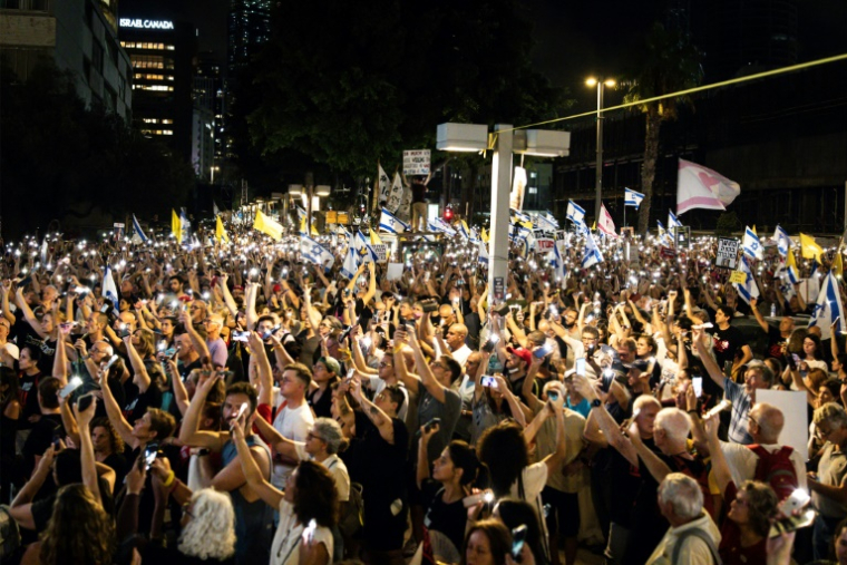 Des manifestants à Tel-Aviv brandissent leurs téléphones portables allumés lors d'une manifestation appelant à un accord en vue d'un cessez-le-feu à Gaza et de la libération des otages, le 26 août 2025 ( AFP / JOHN WESSELS )