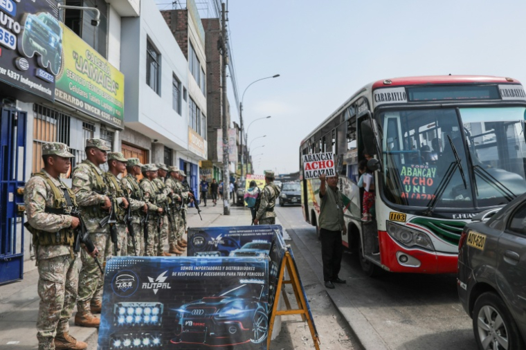 Des soldats montent la garde devant un arrêt de bus à Lima, le 18 mars 2025, un jour après que le Pérou a déclaré l'état d'urgence dans la capitale à la suite d'une série d'assassinats liés au fléau de l'extorsion ( AFP / CONNIE FRANCE )