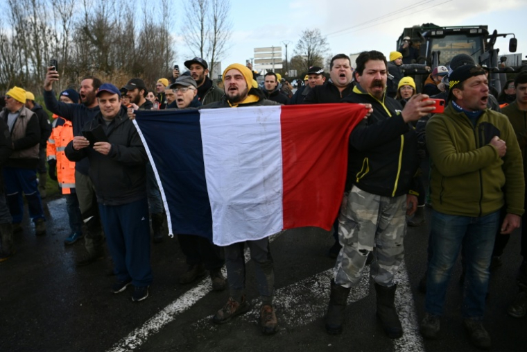 Des agriculteurs tiennent un drapeau français lors d'une intervention des forces de l'ordre pour mettre fin au blocage du dépôt de carburant de Bassens, près de Bordeaux, le 10 janvier 2026 ( AFP / Christophe ARCHAMBAULT )