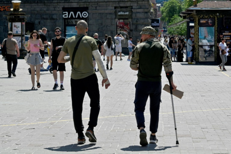 Des soldats ukrainiens blessés marchent dans le centre de Kiev le 6 juillet 2025 ( AFP / Sergei SUPINSKY )