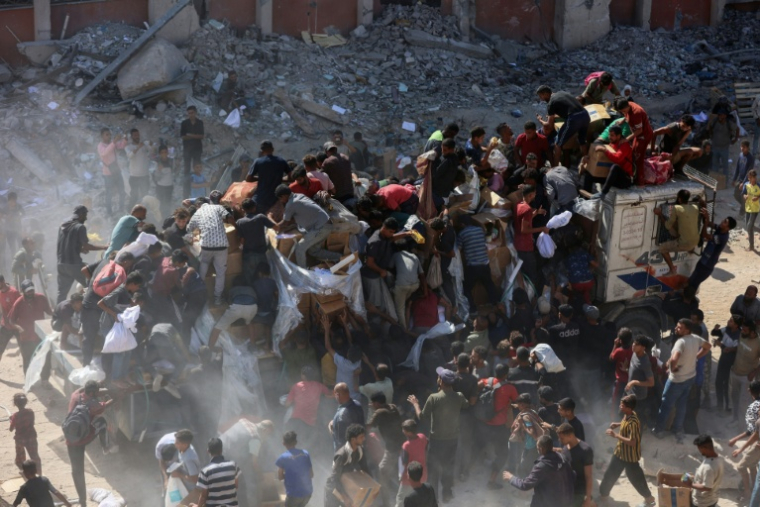 Des Palestiniens se précipitent sur un camion d'aide humanitaire à Khan Younès, dans le sud de la bande de Gaza, le 12 octobre 2025 ( AFP / Omar AL-QATTAA )