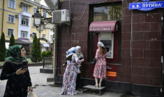 Des femmes se tiennent devant un distributeur de billets situé sur l'avenue Vladimir Poutine à Grozny, en Tchétchénie, le 26 juillet 2019 ( AFP / Alexander NEMENOV )