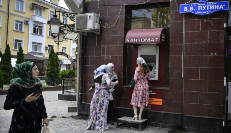 Des femmes se tiennent devant un distributeur de billets situé sur l'avenue Vladimir Poutine à Grozny, en Tchétchénie, le 26 juillet 2019 ( AFP / Alexander NEMENOV )