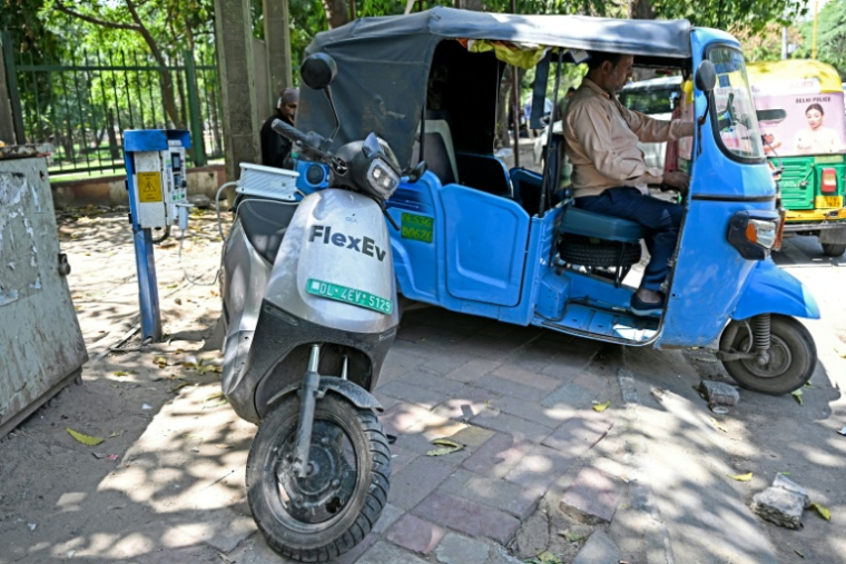 Un conducteur de rickshaw recharge son véhicule à côté d'un scooter électrique, à New Delhi, en Inde, le 12 avril 2026 ( AFP / Sajjad HUSSAIN )