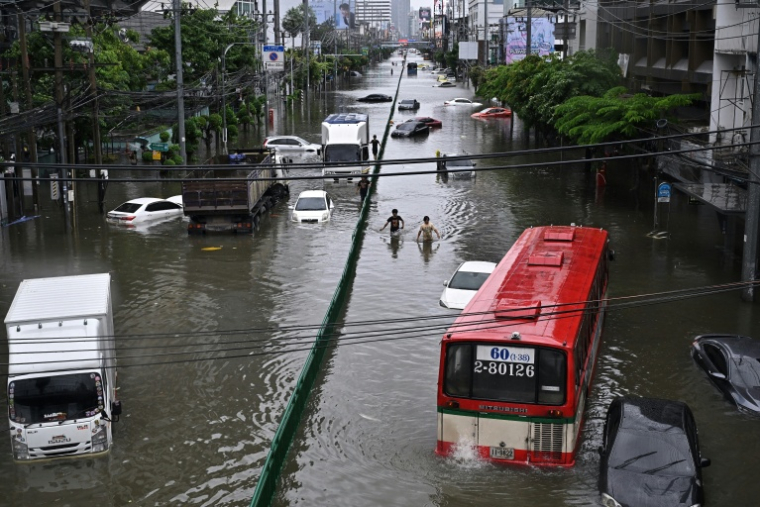 Des passants marchent le long d’une route inondée de Petchaburi à Bangkok, le 26 septembre 2026 ( AFP / Lillian SUWANRUMPHA )