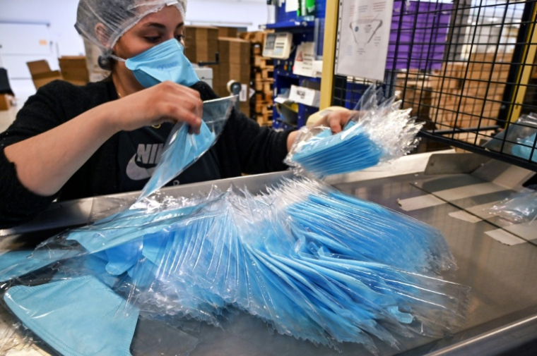 Une employé emballe des masques de protection sur une chaîne de montage d'une usine de fabrication à Mably, le 28 février 2020 dans la Loire ( AFP / PHILIPPE DESMAZES )