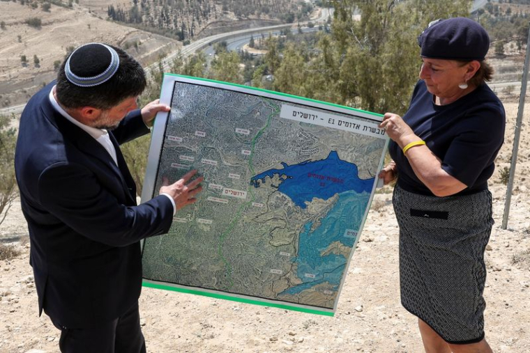 Le ministre israélien des Finances Bezalel Smotrich et une femme tiennent une carte qui montre le projet de colonisation E1