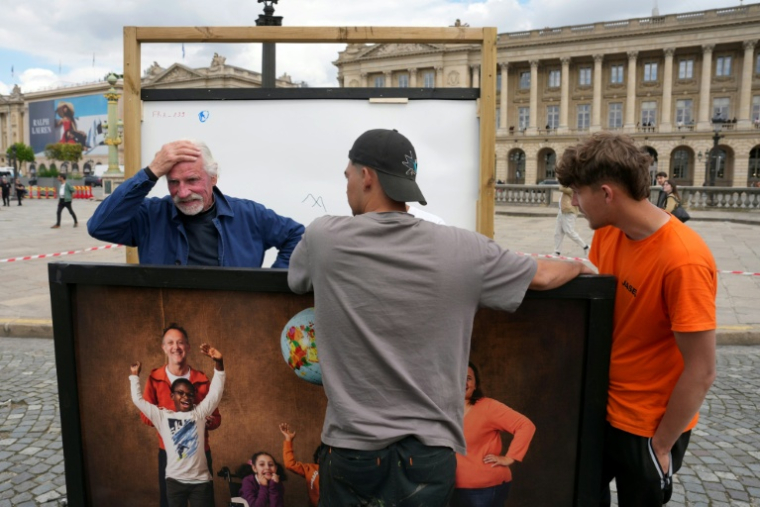 Le photographe Yann Arthus-Bertrand (G) avec des volontaires ayant aidé à la remise en place de l'exposition photos en plein air sur la place de la Concorde à Paris, le 7 mai 2026 ( AFP / Dimitar DILKOFF )