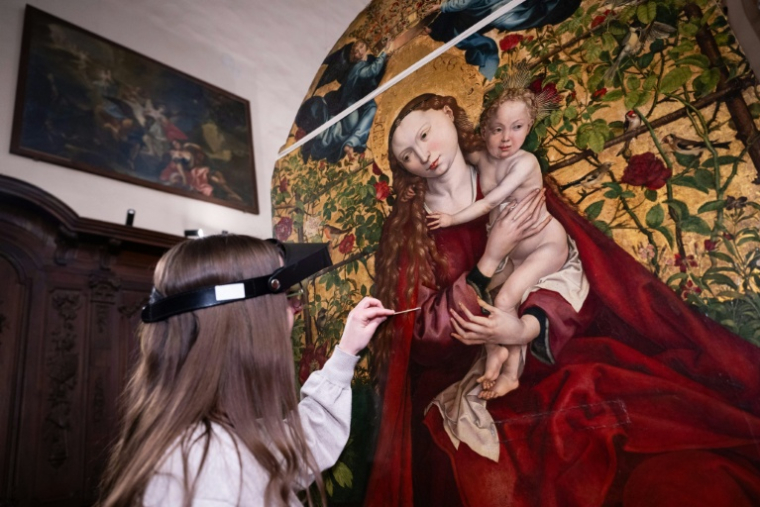 Une experte travaille à la restauration de "La Vierge au buisson de roses" peinte en 1473 par Martin Schongauer, le 5 mars 2026 dans l'église des Dominicains à Colmar, dans le Haut-Rhin ( AFP / SEBASTIEN BOZON )