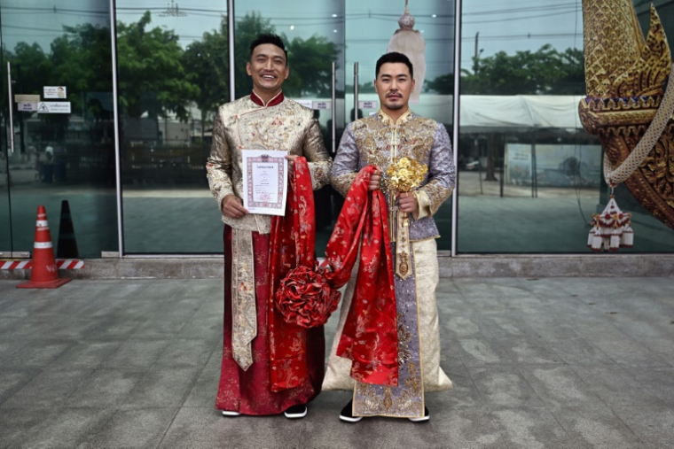 es Chinois Song Jihan (d) et Wang Zengyi montrent le certificat d'enregistrement de leur mariage devant un bureau de district à Bangkok, le 29 mai 2025 en Thaïlande ( AFP / Lillian SUWANRUMPHA )