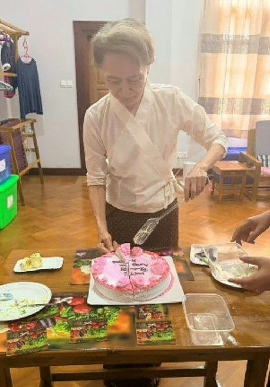 Cette photo d'archive non datée, diffusée le 3 août 2026 par le Bureau présidentiel de la presse et de l'information (PPIB) de Birmanie, montre l'ancienne dirigeante et prix Nobel de la paix Aung San Suu Kyi, actuellement détenue en résidence surveillée, en train de couper un gâteau. ( Myanmar's Presidential Press and Information Bureau / Handout )