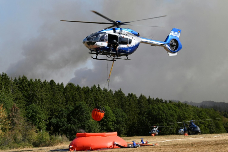 Des hélicoptères de la police chargent de l'eau pour lutter contre un incendie de forêt à Hurtgenwald, dans l'ouest de l'Allemagne, le 14 août 2026 ( AFP / Roberto Pfeil )
