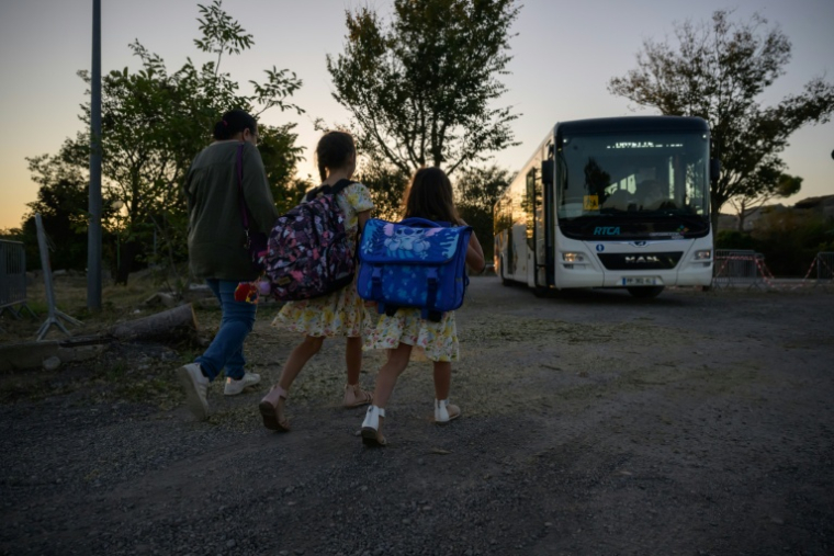 Des enfants de l'école de Pomas dans l'Aude, détruite par une tornade, rejoignent un bus pour se rendre dans une école provisoire pour la rentrée des classes le 1er septembre 2026 ( AFP / Ed JONES )