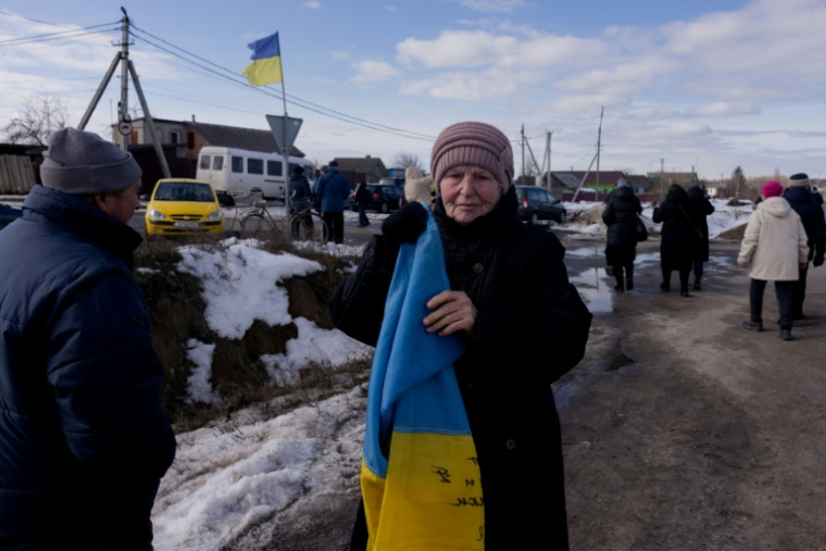 Une femme tient un drapeau ukrainien pour accueillir un convoi de soldats libérés par les Russes après un échange de prisonniers, le 6 mars 2026 dans un lieu non précisé dans le nord de l'Ukraine ( AFP / Tetiana DZHAFAROVA )