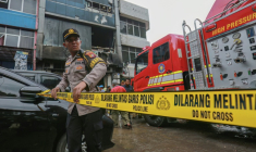 Un membre de la police indonésienne barre l'accès à l'immeuble qui a pris feu à Jakarta le 9 décembre 2025 ( AFP / SYNATRIA RESPATI )