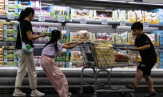 Une femme et deux enfants font leurs courses devant un rayon de fromages réfrigérés dans un supermarché de Pékin