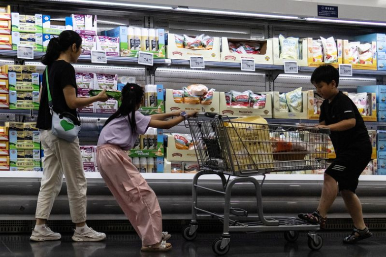 Une femme et deux enfants font leurs courses devant un rayon de fromages réfrigérés dans un supermarché de Pékin