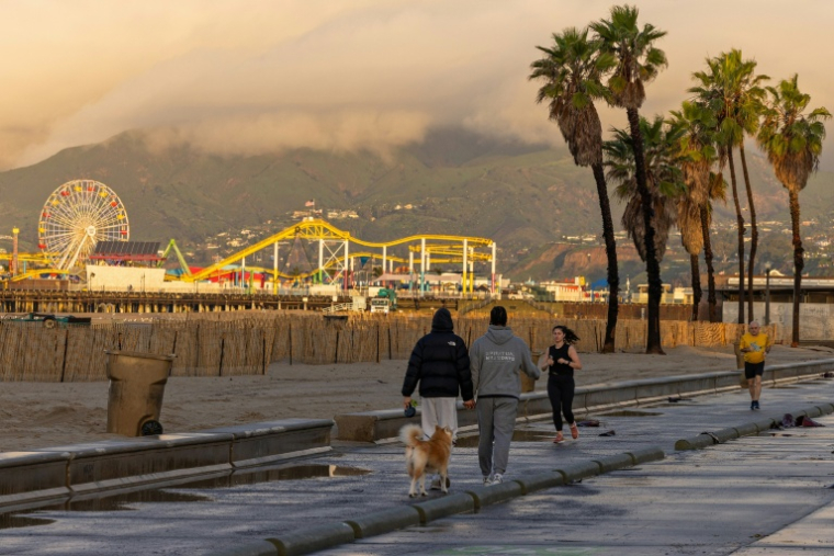 Des passants profitent d'une brève accalmie météo, le 25 décembre 2025 à Santa Monica, en Californie ( AFP / Jonathan ALCORN )