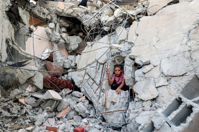 Un garçon sort de décombres après l'effondrement d'un bâtiment touché par un bombardement dans le camp de Nousseirat, dans le centre de la bande de Gaza, le 30 août 2025 ( AFP / Eyad BABA )