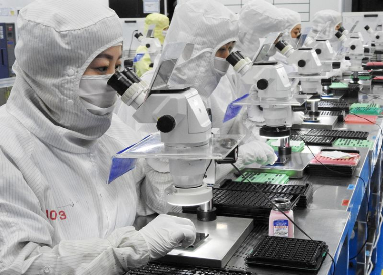 Des employés travaillent sur une ligne de production fabriquant des lentilles d'appareil photo pour téléphones portables dans une usine de Lianyungang, Jiangsu