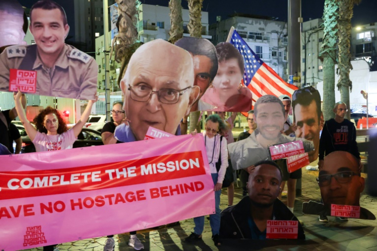 Des Israéliens brandissent des portraits d'otages décédés toujours retenus par le Hamas dans la bande de Gaza, lors d'un rassemblement devant l'antenne de l'ambassade américaine à Tel-Aviv, le 21 octobre 2025 ( AFP / Jack GUEZ )