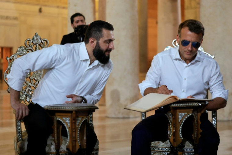 Le président français Emmanuel Macron (d) signe un livre aux côtés du président syrien Ahmed Al-Chareh lors d'une visite à la mosquée des Omeyyades à Damas, le 6 juillet 2026 ( POOL / Ludovic MARIN )
