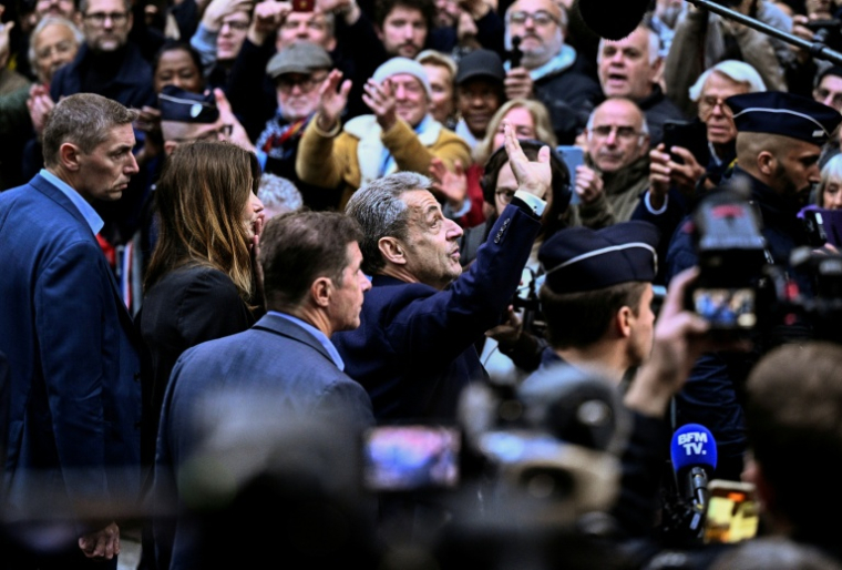 L'ancien président Nicolas Sarkozy salue ses partisans rassemblés devant sa résidence qu'il quitte pour se rendre à la prison de la Santé, le 21 octobre 2025 à Paris ( AFP / JULIEN DE ROSA )