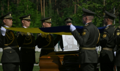 Des militaires de la garde d’honneur ukrainienne tiennent des drapeaux nationaux au-dessus des cercueils contenant les dépouilles d’Andriy Melnyk, mort en 1964 et chef d’une branche de l’Organisation des nationalistes ukrainiens (OUN) lors de leur cérémonie de réinhumation au cimetière militaire national près de Kiev, le 25 mai 2026 ( AFP / Genya SAVILOV )